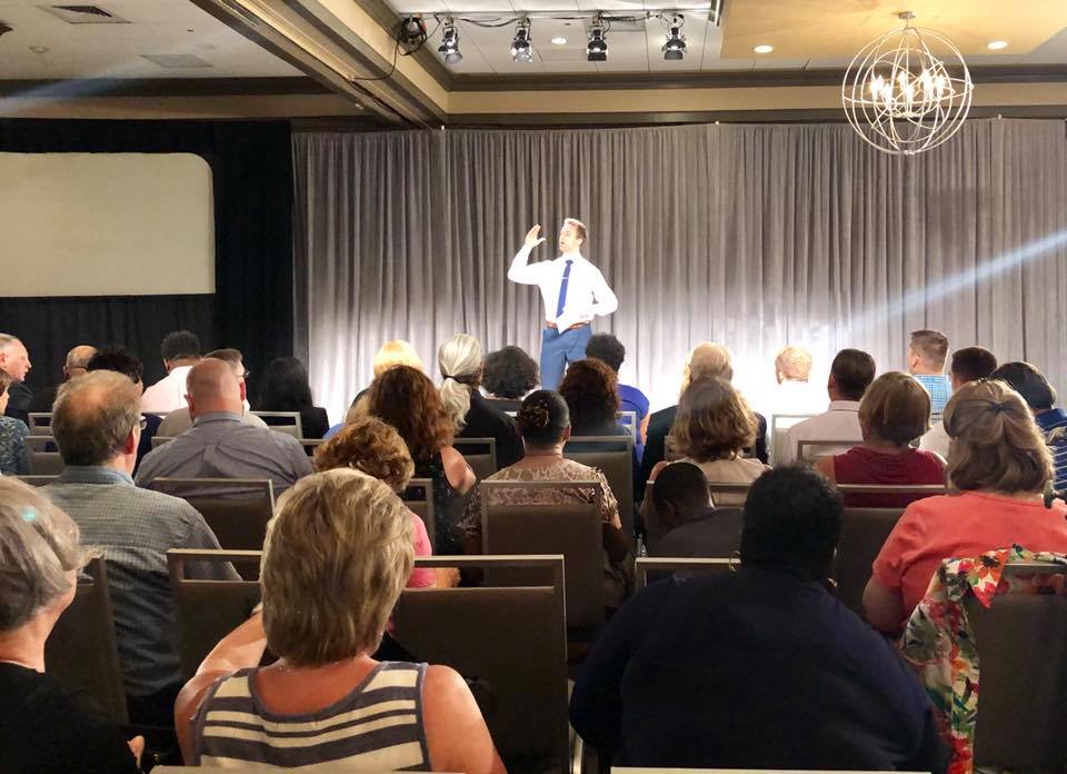 Adam Ranville speaking on stage to an audience